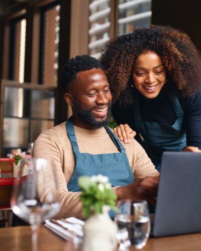 black business couple looking at a laptop and smiling